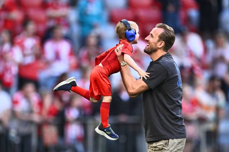 Munich's Harry Kane plays with his child on the pitch after the German Bundesliga soccer match between Bayern Munich and VfL Wolfsburg at Allianz Arena. Tom Weller/dpa