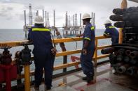 FILE PHOTO: Crew members look over idle oil rigs in the Gulf of Mexico near Port Fourchon, Louisiana