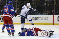 New York Rangers goaltender Igor Shesterkin (31) lies on the puck after making a save as Tampa Bay Lightning right wing Corey Perry (10) jumps over him during the first period of an NHL hockey game, Sunday, Jan 2, 2022, at Madison Square Garden in New York. (AP Photo/Rich Schultz)