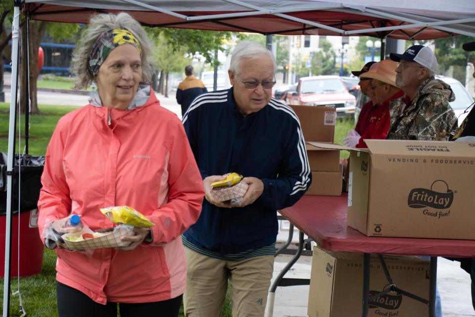 Lana and Tim Baker grab lunch Wednesday at High Noon on the Square in downtown Amarillo. The Coors Cowboy Club & Rodeo provided lunch by serving hamburgers prepared by the Coors Cowboy Club Cook Team, ahead of their annual cattle drive and rodeo this week.