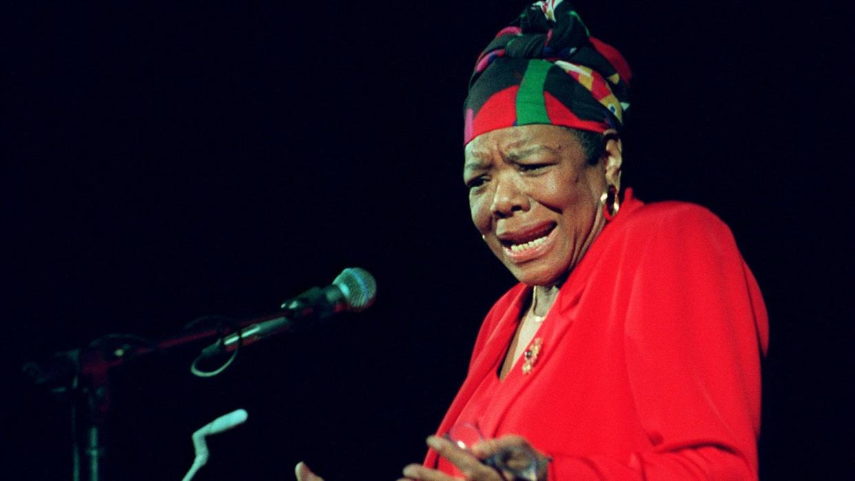 maya angelou wearing a red dress and gesturing with her hands as she reads poetry at a podium