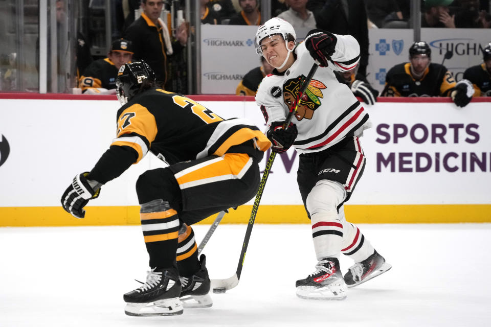 Chicago Blackhawks' Connor Bedard, right, gets off a slap shot with Pittsburgh Penguins' Ryan Graves defending during the first period of an NHL hockey game in Pittsburgh, Tuesday, Oct. 10, 2023. (AP Photo/Gene J. Puskar)