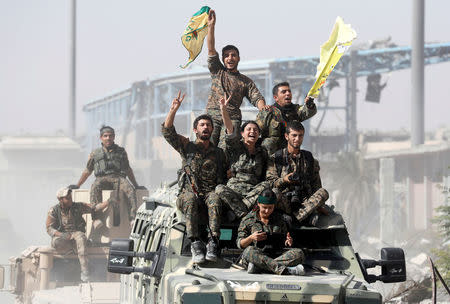 Syrian Democratic Forces fighters ride atop military vehicles as they celebrate victory in Raqqa, Syria. REUTERS/Erik De Castro