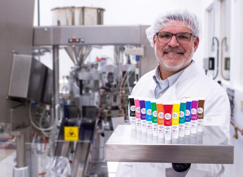 Ben Clark with his company's line of food coloring in front of the machine that makes it.