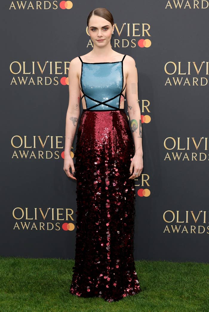 Woman in a blue top and red sequined skirt posing at the Olivier Awards