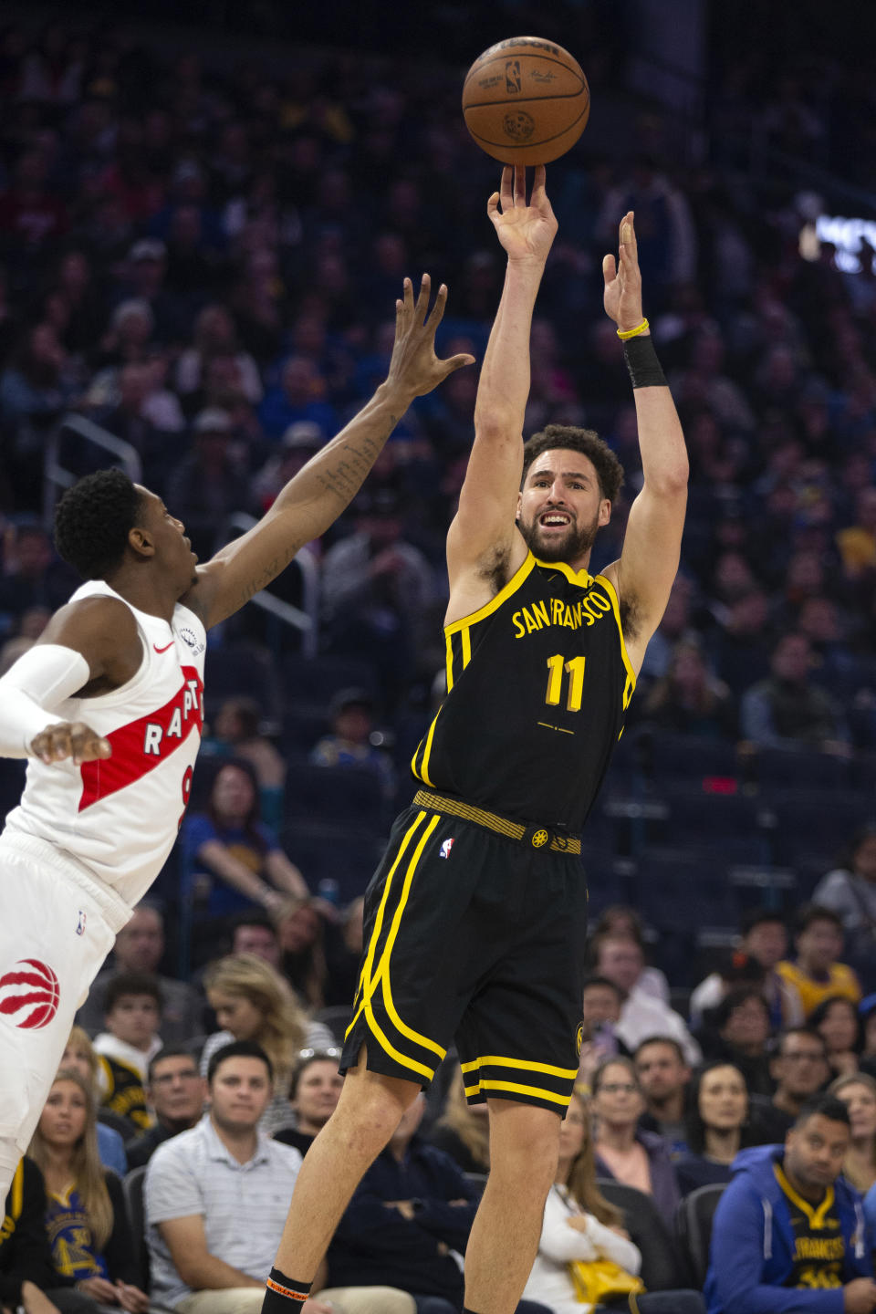 Golden State Warriors guard Klay Thompson (11) shoots over Toronto Raptors forward RJ Barrett, left, during the first quarter of an NBA basketball game, Sunday, Jan. 7, 2024, in San Francisco. (AP Photo/D. Ross Cameron)