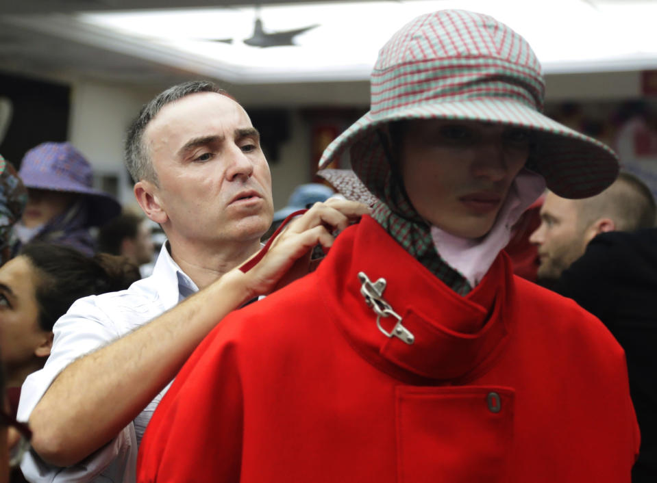 FILE - In this Tuesday, July 11, 2017 file photo, Fashion designer Raf Simons, left, makes adjustments before his fashion show during Men's Fashion Week in New York. Designer Raf Simons is parting ways with Calvin Klein after two years with the fashion company. Calvin Klein announced in a statement Friday, Dec. 21, 2018 the Belgian designer's departure as the chief creative officer was amicable. The company said it decided on a new brand direction different from Simons' creative vision. (AP Photo/Frank Franklin II, File)