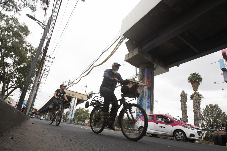 Bicyclists pedal past the site where an elevated section of the subway Line 12 collapsed in early May, in Mexico City, Thursday, June 17, 2021. A visual inspection has found problems in about one-third of the elevated Line 12, one span of which collapsed on May 3, killing 26 people. (AP Photo/Marco Ugarte)