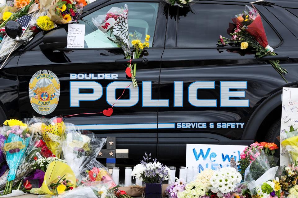 Flowers drape a police vehicle outside the Boulder Police Department after a shooting rampage at a Boulder supermarket on March 22 left 10 people dead, including officer Eric Talley, 51, a father of seven who responded to the 911 call.