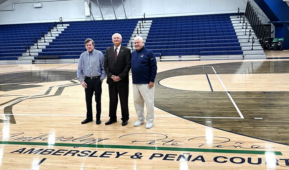 Standing with Pensacola State College president Ed Meadows (middle), Joe Ambersley and Pete Pena (blue jacket) stand in front of renamed court in their honor at PSC's Hartsell Arena.