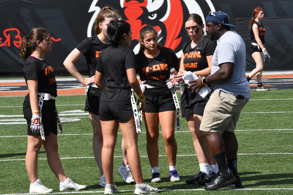Coach Desmon Gault of Mount Notre Dame goes over the next play call with his players at the girls flag football kickoff jamboree sponsored by USA Football and the Cincinnati Bengals at Paycor Stadium, Sept. 30, 2023.