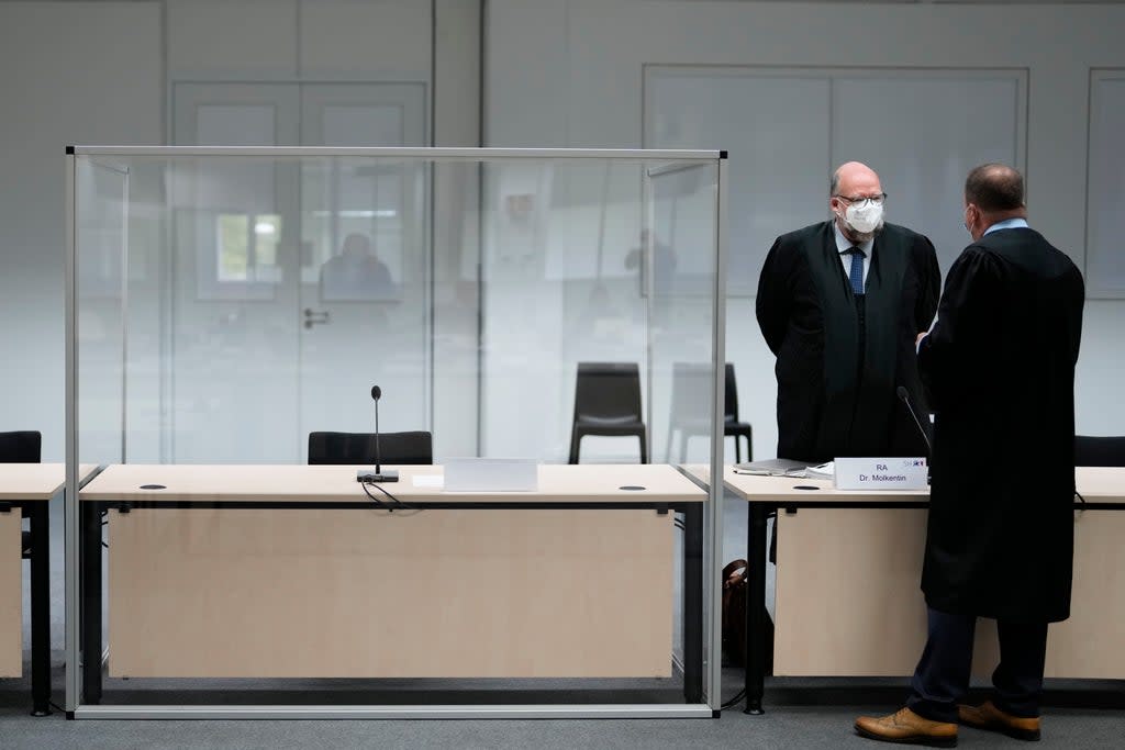 Two lawmakers stand next to an empty seat at the courtroom  (AP)