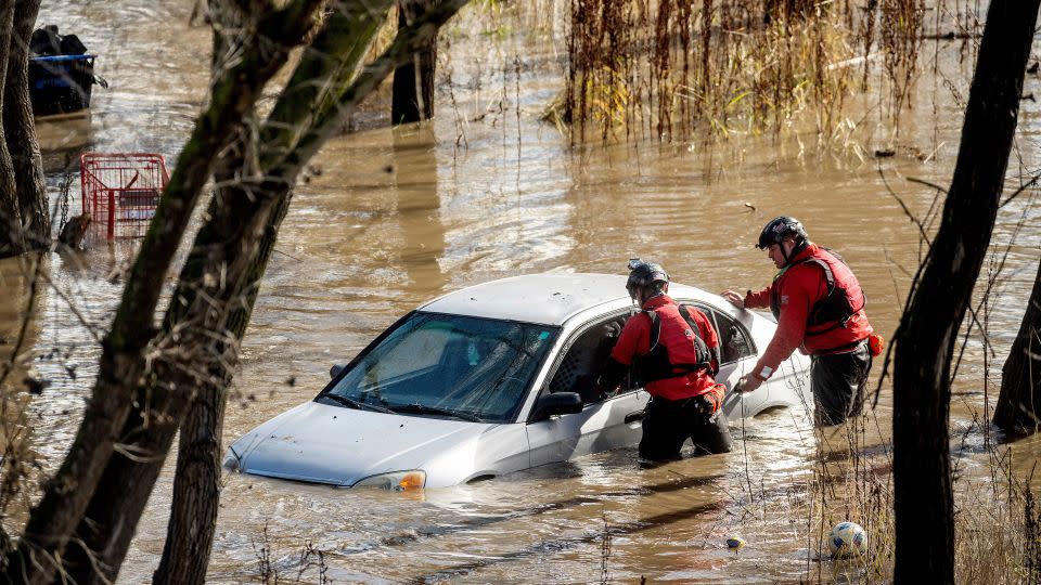 Search and rescue workers investigate a car surrounded by floodwaters in San Jose, California. - Noah Berger/AP