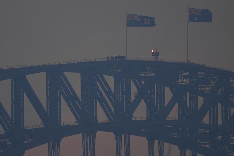 Climbers on the Sydney Harbour bridge as smoke haze from bushfires blankets the city.