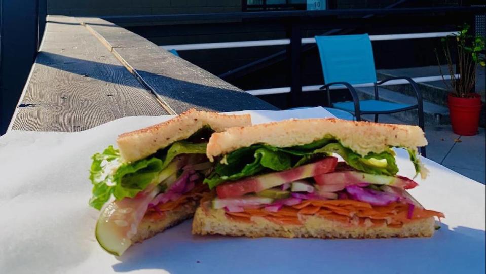 The House Veggie Sandwich is stacked with hummus, lettuce, carrots, tomato, onion and pickles.