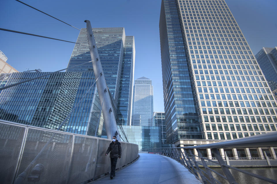 A man wearing a protective face mask walks in Canary Wharf, London during rush hour, after Prime Minister Boris Johnson has put the UK in lockdown to help curb the spread of the coronavirus.