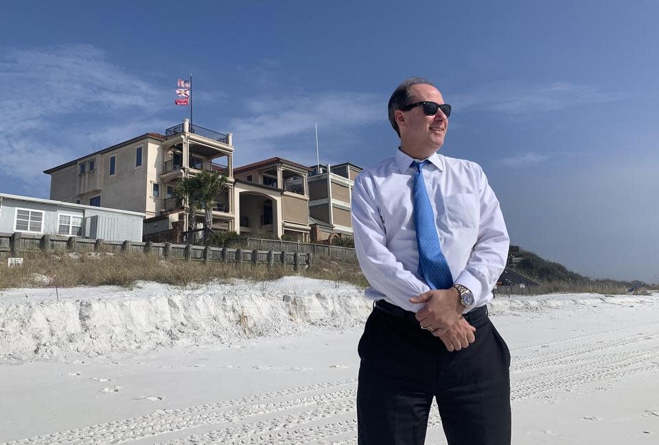 Attorney Daniel Uhlfelder poses on the beach in South Walton County in front of Gov. Mike Huckabee's home.