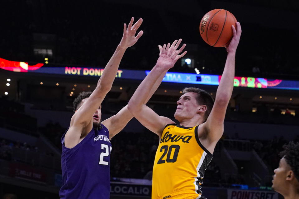 CORRECTS ID TO NORTHWESTERN FORWARD PETE NANCE, NOT NORTHEASTERN GUARD QUIRIN EMANGA - Iowa guard Payton Sandfort (20) shoots over Northwestern forward Pete Nance (22) in the first half of an NCAA college basketball game at the Big Ten Conference tournament in Indianapolis, Thursday, March 10, 2022. (AP Photo/Michael Conroy)