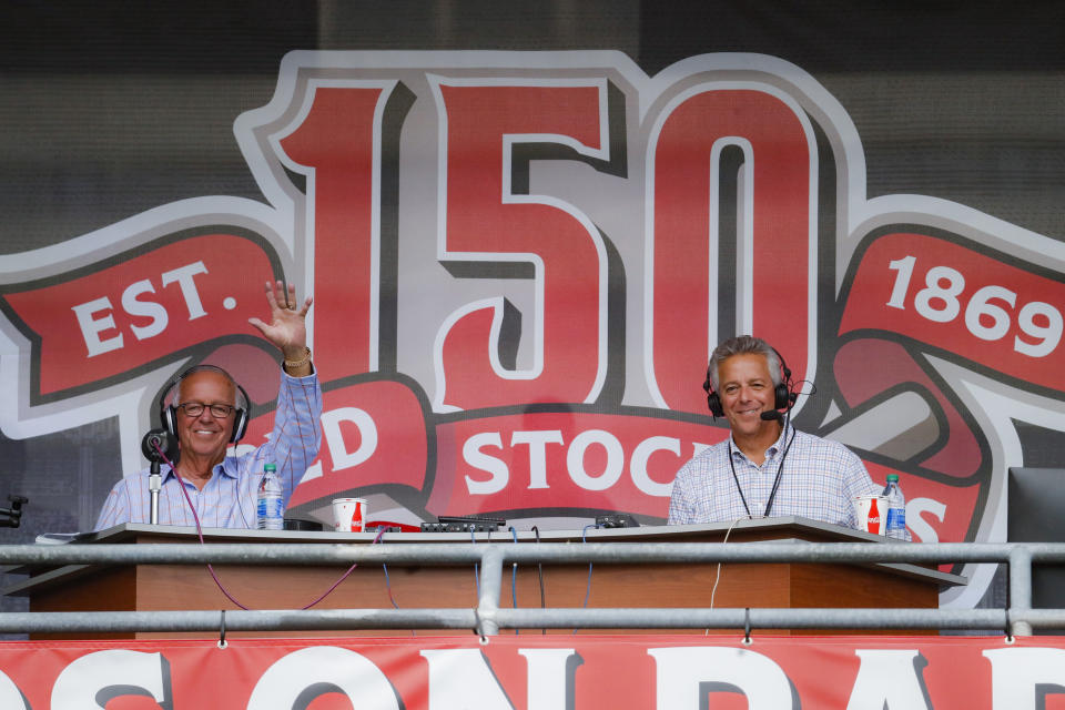 Cincinnati Reds radio announcer Marty Brennaman, left, waves next to his son Thom, in a special outside booth before the Reds' baseball game against the Milwaukee Brewers, Wednesday, Sept. 25, 2019, in Cincinnati. (AP Photo/John Minchillo)