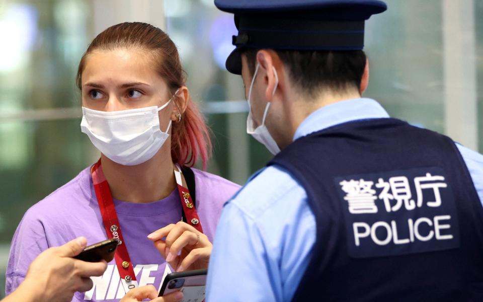 Belarusian sprinter Krystsina Tsimanouskaya talks with police officers at Haneda international airport in Tokyo, Japan - ISSEI KATO /REUTERS