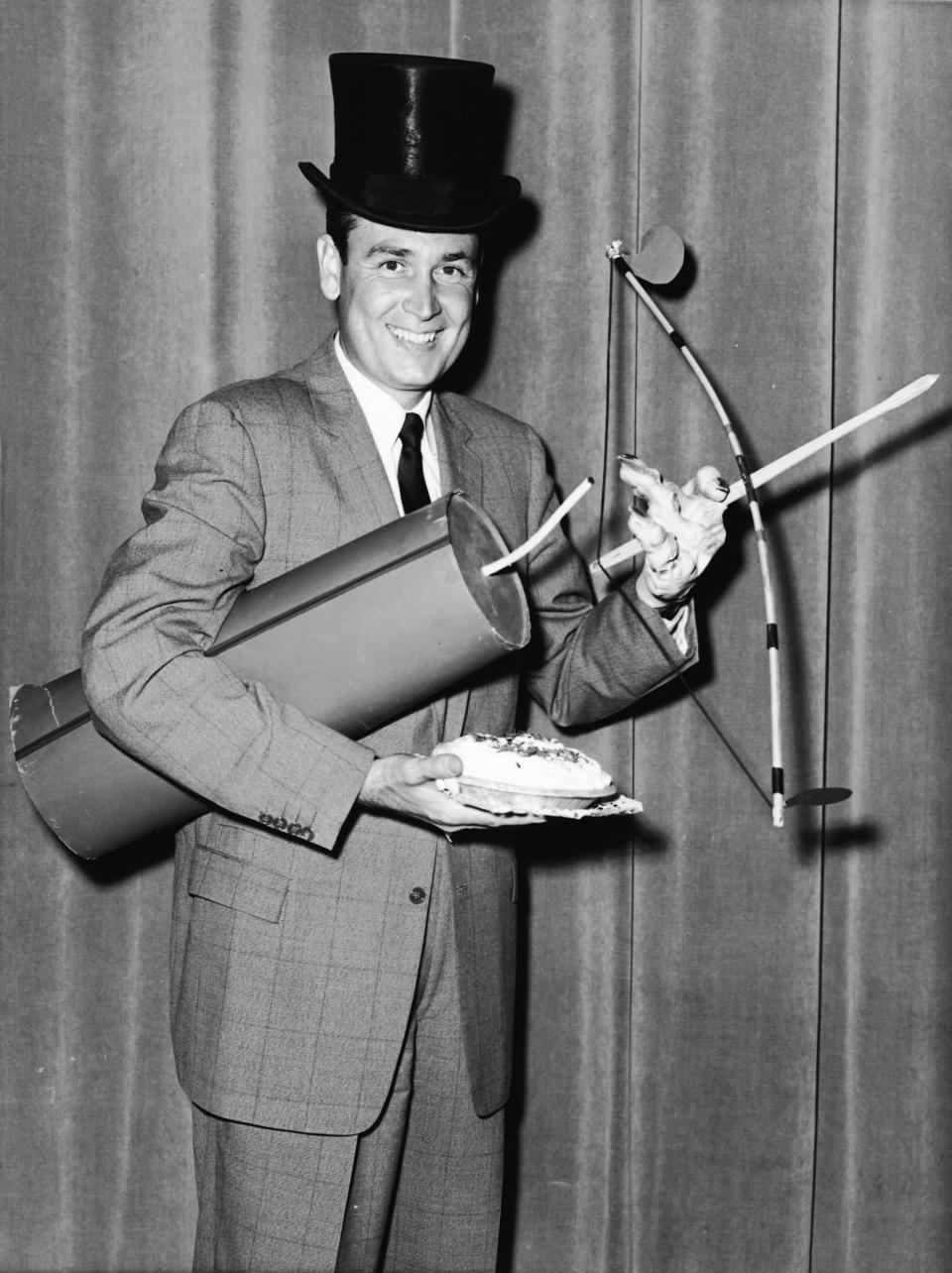 Publicity portrait of American radio and television show host Bob Barker as he poses with a number of props in preparation for hosting the television show 'Truth or Consequences,' January 4, 1957. The props include an oversized firecracker, a top hat, a cream pie, a rubber hand, and a toy bow and arrow set. (Photo by FPG/Getty Images)