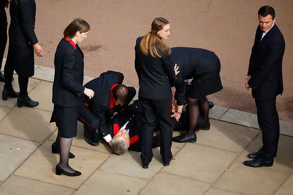 LONDON, ENGLAND - SEPTEMBER 19: A Buckingham Palace household staff person collapses outside Buckingham Palace after paying their respects during the State Funeral of Queen Elizabeth II on September 19, 2022 in London, England. Elizabeth Alexandra Mary Windsor was born in Bruton Street, Mayfair, London on 21 April 1926. She married Prince Philip in 1947 and ascended the throne of the United Kingdom and Commonwealth on 6 February 1952 after the death of her Father, King George VI. Queen Elizabeth II died at Balmoral Castle in Scotland on September 8, 2022, and is succeeded by her eldest son, King Charles III.  (Photo by Chip Somodevilla/Getty Images)