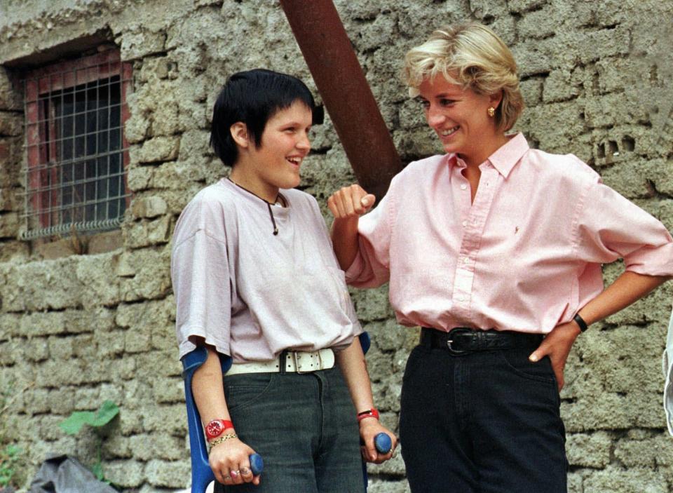 FILE - In this file photo dated Sunday Aug. 10, 1997, Britain's Diana, Princess of Wales, right, chats with 15-year old landmine victim Bosnian muslim girl Mirzeta Gabelic, in front of Mirzeta's home in Sarajevo, while Diana was on a visit to the region as part of her campaign against landmines. The Princess died 20-years ago after a car crash Sunday, Aug. 31, 1997, in Paris, and the legacy left by Princess Diana seems to live on through her two sons, who have adopted their mother’s more personal approach to the monarchy and to the public. (AP Photo /Hidajet Delic, File)