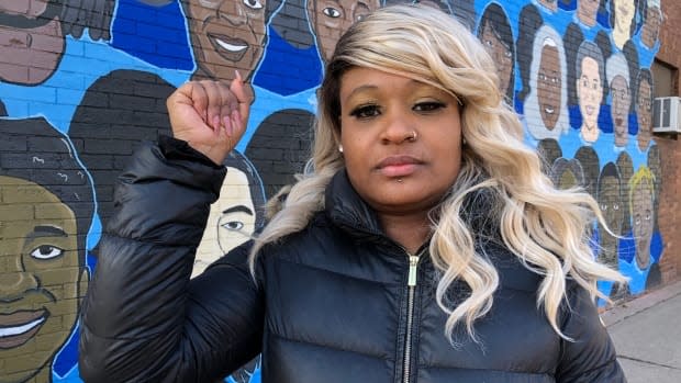 Toshira Garraway, who founded Families Supporting Families Against Police Violence, stands in front of a mural of Minnesotans who have died after police encounters.