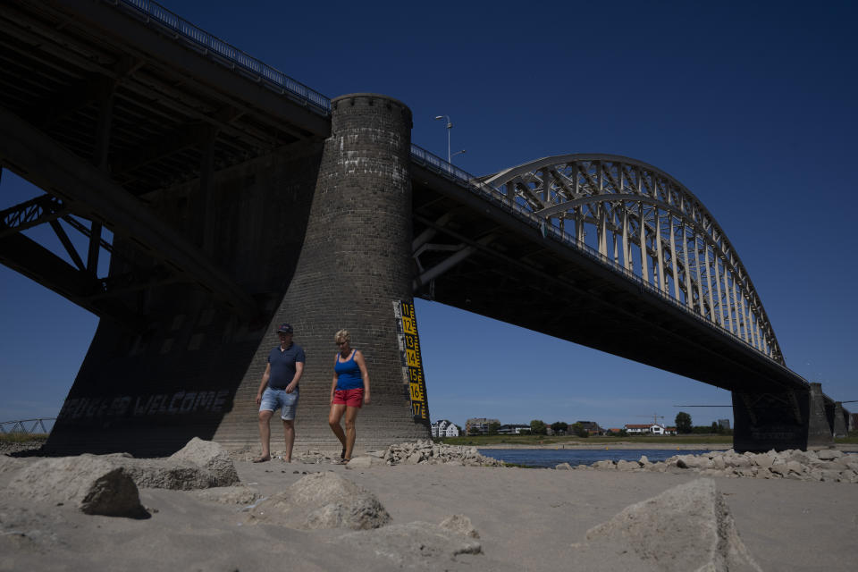 FILE - People take a stroll on the river bed of the Waal as water levels dropped because of drought in Nijmegen, Netherlands, Tuesday, Aug. 9, 2022. In parts of the country a ban on daytime irrigation of agricultural land has been issued because of extreme drought. (AP Photo/Peter Dejong, File)