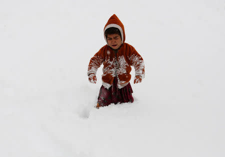 An Internally displaced Afghan child cries as he gets stuck in waist-deep snow outside his shelter during a snowfall in Kabul, Afghanistan February 5, 2017. REUTERS/Mohammad Ismail