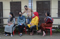 Nagas wearing face masks as a preventive measure against the coronavirus and sit outside a polling booth during by-elections in Kohima, capital of the northeastern Indian state of Nagaland, Tuesday, Nov. 3, 2020. Elections are being held in two constituencies in the state after the seats fell vacant following the demise of their respective lawmakers. (AP Photo/Yirmiyan Arthur)