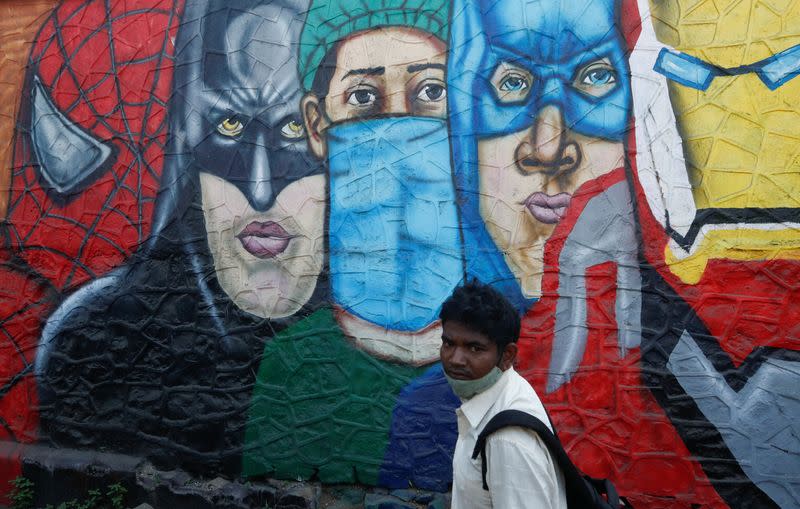 A man walks past a mural on a street, amidst the spread of COVID-19, in Mumbai