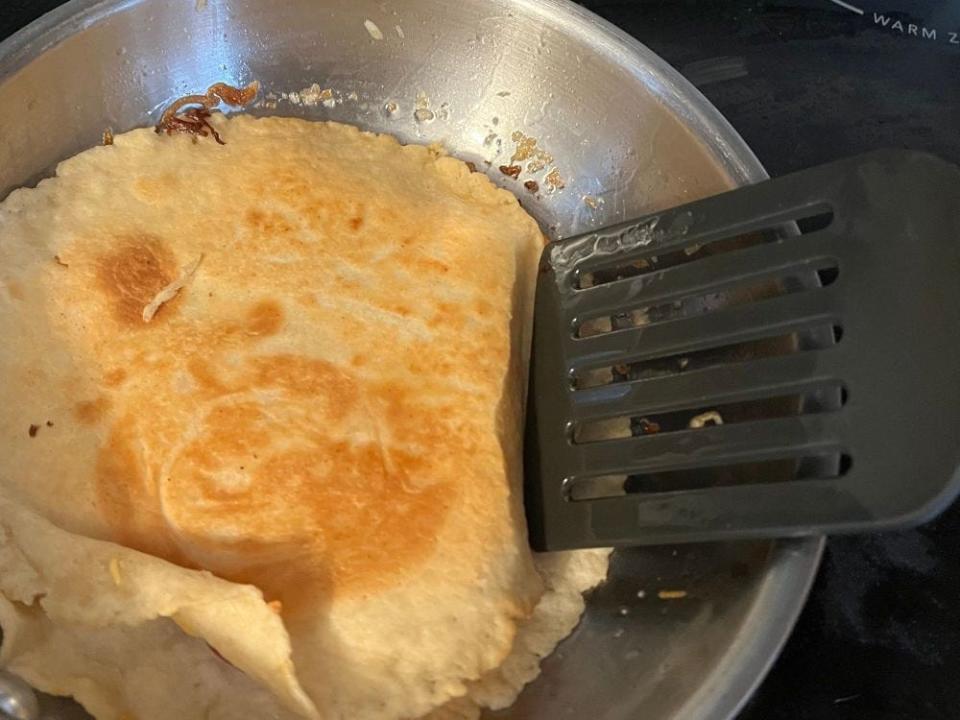 spatula moving a tortilla around in a pan over the stove