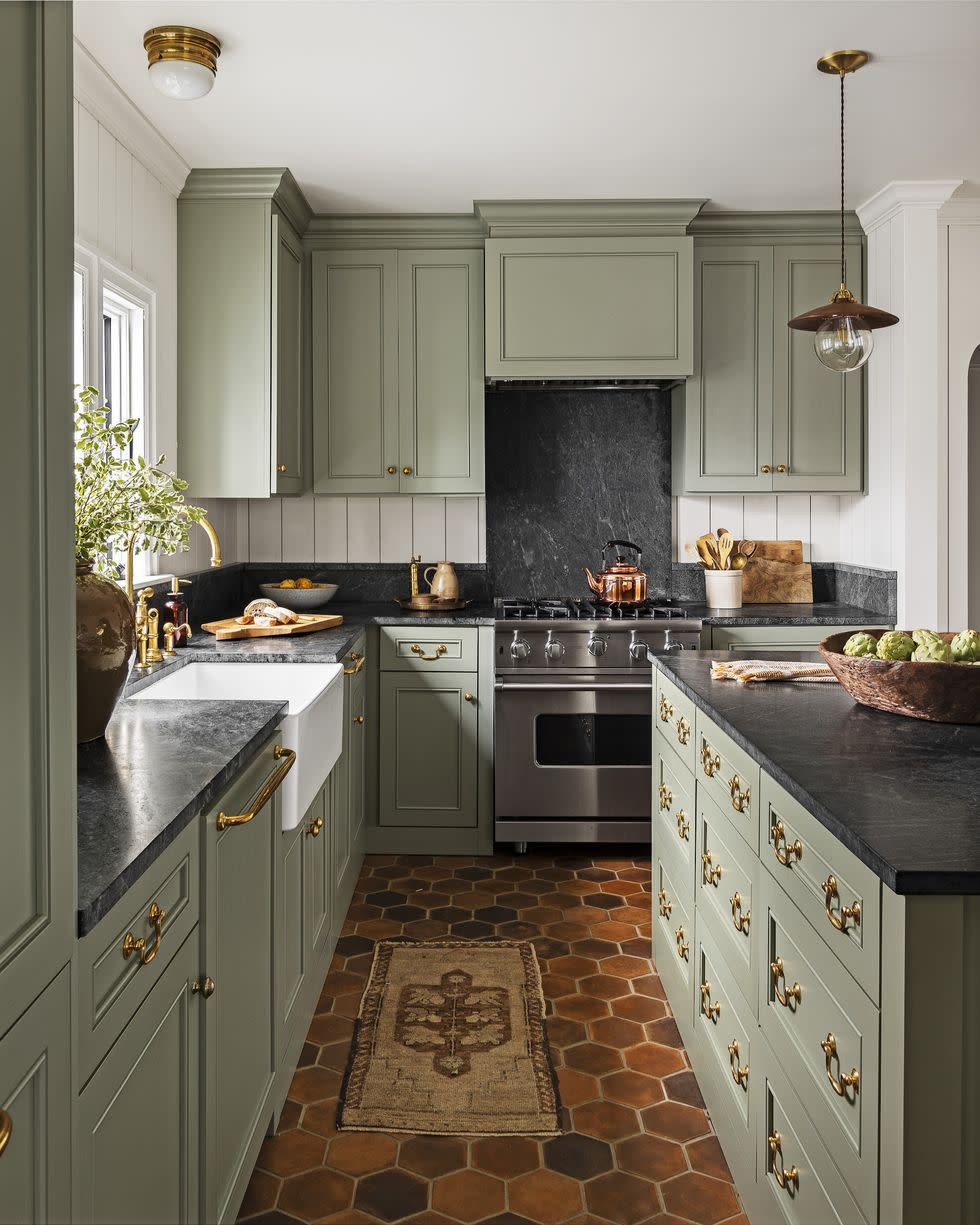 kitchen with gray green cabinets, black stone counters, and terra cotta hexagon tile floor