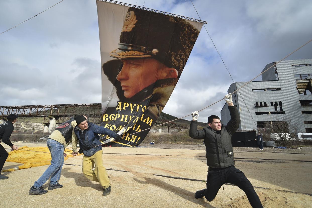 Enthusiasts fix a portrait of Russian President Vladimir Putin to a balloon during celebration of the anniversary of Crimea annexation from Ukraine in 2014, in Sevastopol, Crimea, Thursday, March 18. Residents of cities in Crimea and Russia are holding gatherings to commemorate the seventh anniversary of Russia's annexation of the Black Sea peninsula from Ukraine. 