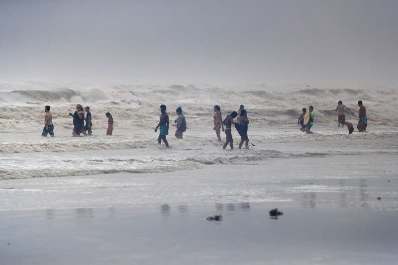 Beach-goers play in high swells from Hurricane Hanna in Galveston, Texas