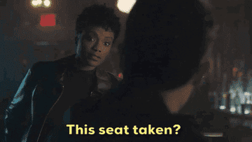 Woman going up to bar saying "this seat taken?"