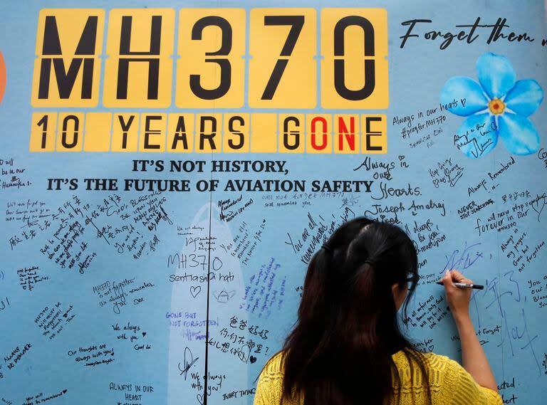 Una mujer escribe un mensaje en un panel durante un acto para conmemorar los 10 años de la desaparición del vuelo MH370 de Malaysia Airlines, en un centro comercial en Subang Jaya, en las afueras de Kuala Lumpur, Malasia