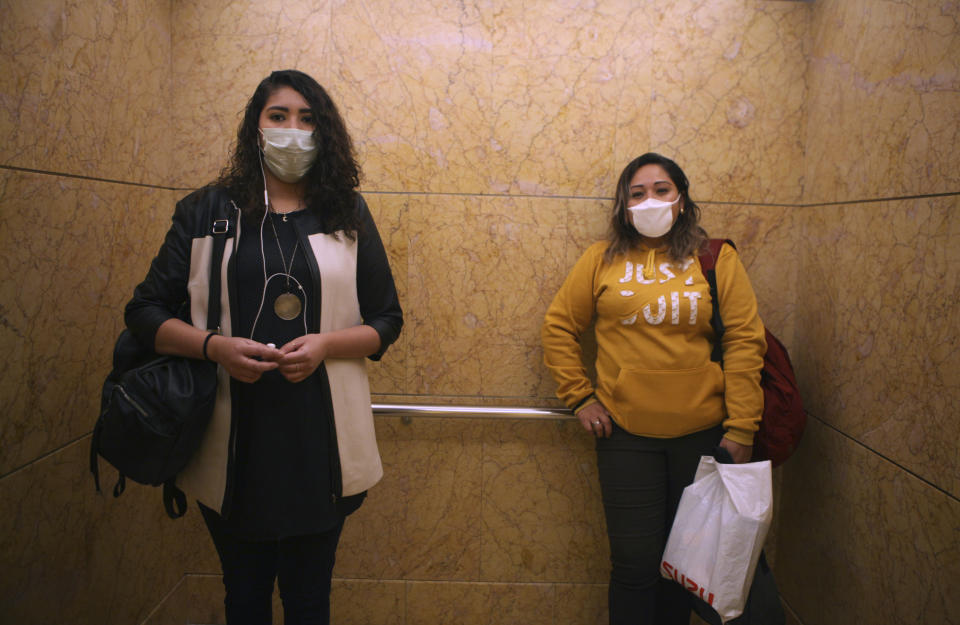 Women wear face masks as a precaution against the spread of the new coronavirus as they ride the elevator to their offices in Mexico City, Thursday, March 19, 2020. (AP Photo/Marco Ugarte)
