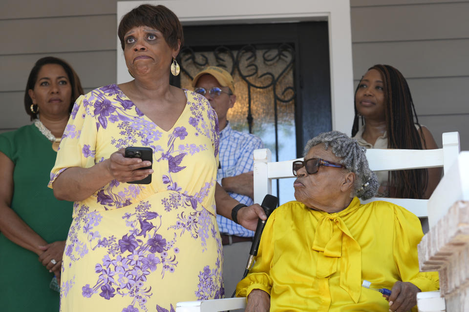 Opal Lee, right, sits in a rocking chair while her granddaughter Magistrate Judge Renée Toliver pauses while telling the story of Lee's parents and the home site in Fort Worth, Texas, Friday, June 14, 2024. Habitat for Humanity built Lee a new home on the same lot where a white mob destroyed Toliver's great grandparents just purchased home over 80 years ago. (AP Photo/LM Otero)