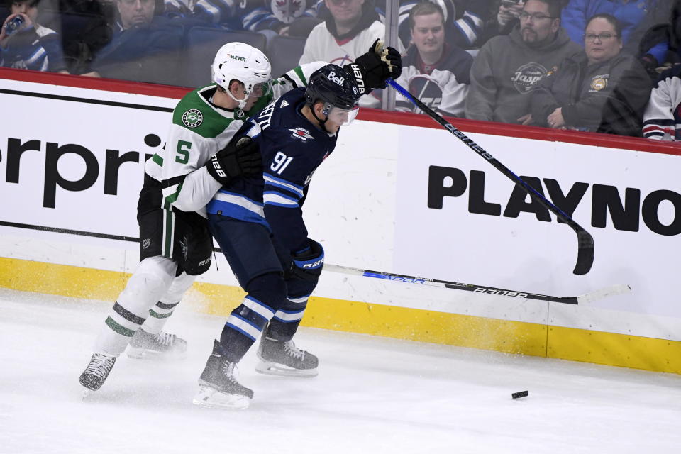 Winnipeg Jets' Cole Perfetti (91) is checked by Dallas Stars' Nils Lundkvist (5) during the third period of an NHL hockey game, Tuesday, Nov. 8, 2022 in Winnipeg, Manitoba. (Fred Greenslade/The Canadian Press via AP)