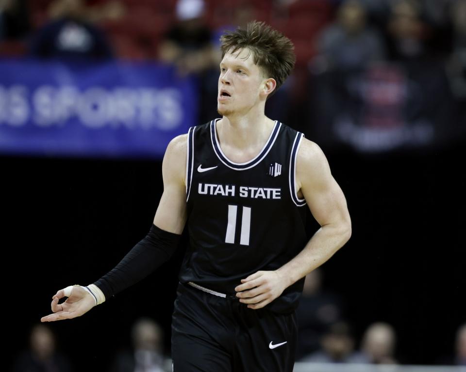 Utah State Aggies guard Max Shulga (wearing black) signals a 3-point make