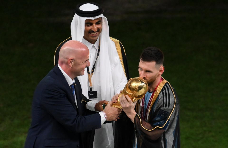 LUSAIL CITY, QATAR - DECEMBER 18: FIFA President Gianni Infantino (L) and Sheikh Tamim bin Hamad Al Thani, Emir of Qatar, present the FIFA World Cup trophy to Lionel Messi of Argentina following the FIFA World Cup Qatar 2022 Final match between Argentina and France at Lusail Stadium on December 18, 2022 in Lusail City, Qatar. (Photo by Stephen McCarthy - FIFA/FIFA via Getty Images)