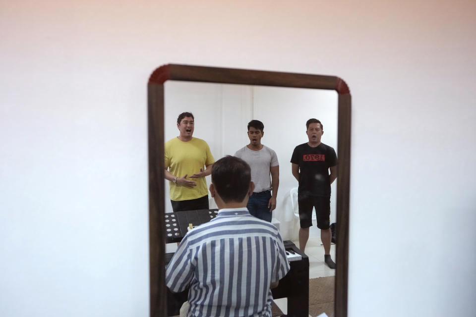 Vocal coach Vuthipand Pongtanalert, front, instructs members of The Bangkok Gay Men's Chorus, reflected on a mirror, during a lesson in Bangkok, Thailand, Sunday, Nov. 26, 2023. Thailand's Parliament is set to debate Thursday, Dec. 21, a final cabinet-endorsed draft bill to pass landmark legislation allowing members of the LGBTQ+ community to get married. (AP Photo/Sakchai Lalit)