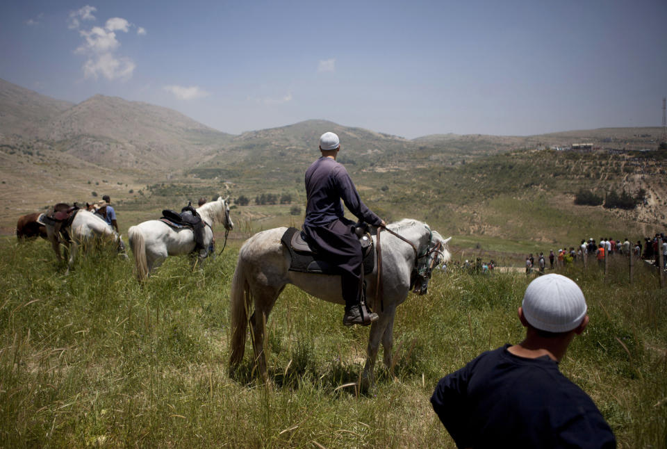 FILE - In this June 5, 2011, file photo, Israeli Druze men watch as pro-Palestinian protesters approach the Israel-Syria border in the Golan Heights. The area is a strategic high ground at the southwestern corner of Syria with stunning, broad views of both Israel and Syria below. (AP Photo/Oded Balilty, File)