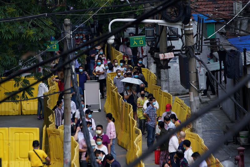 Residents wearing face masks line up for nucleic acid testings at a residential compound in Wuhan