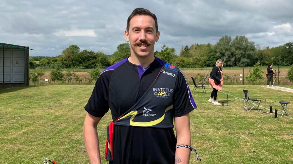 A smiling Richard Davies looking directly at the camera wearing sports clothes in a green field.  