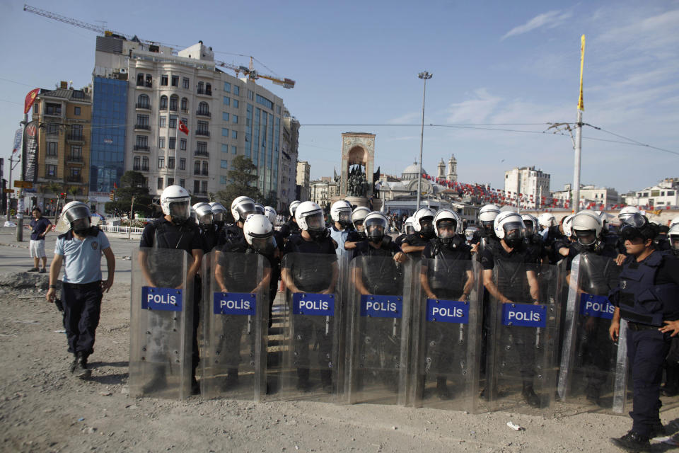 Riot policemen take their position during clashes in Taksim Square in Istanbul, Turkey, Tuesday, June 11, 2013. Hundreds of police in riot gear forced through barricades in Istanbul's central Taksim Square early Tuesday, pushing many of the protesters who had occupied the square for more than a week into a nearby park. (AP Photo/Kostas Tsironis)