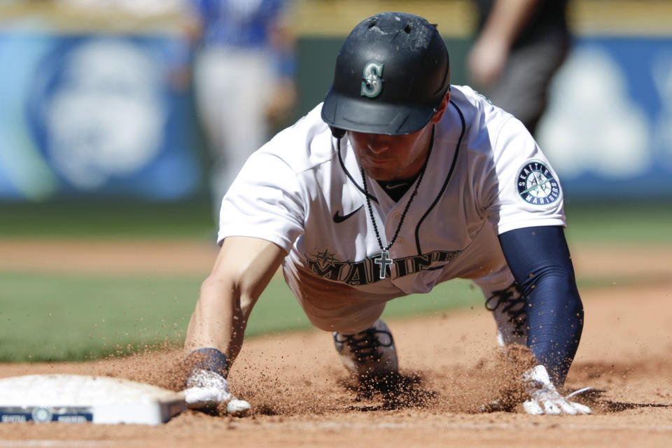 Seattle Mariners' Jarred Kelenic dives back to first on a pickoff attempt by Kansas City Royals starting pitcher Daniel Lynch during the fourth inning of a baseball game Saturday, Aug. 28, 2021, in Seattle. (AP Photo/Jason Redmond)