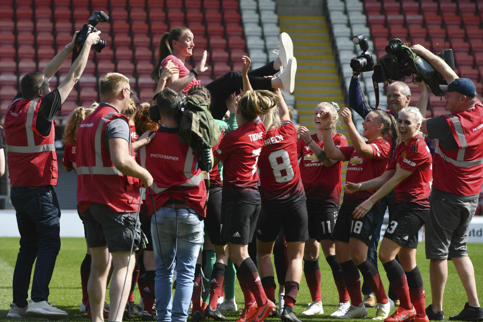 Manchester United manager Casey Stoney, top, is congratulated by players after the final whistle during the FA Women's Championship soccer match between Manchester United and Crystal Palace at Leigh Sports Village, Manchester, England, Saturday April 20, 2019. (Anthony Devlin/PA via AP)